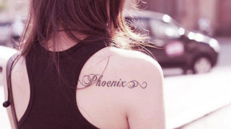 Hình xăm vai sau có chữ ‘Phoenix’ là đại diện cho sự mạnh mẽ, rực sáng và bay cao bay xa như phượng hoàng của nữ giới