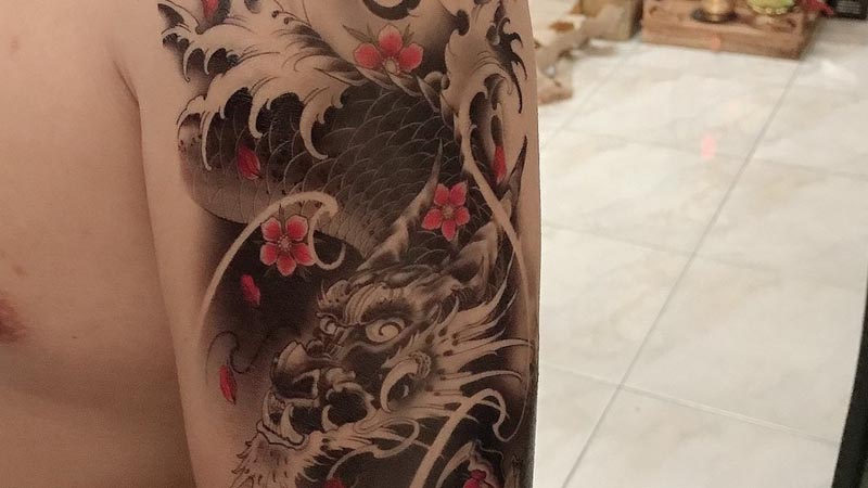 Hình xăm rồng dũng mãnh cùng những bông hoa được điểm tô tạo điểm nhấn hợp lý